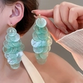 Gedetailleerd zicht op lange muntgroene schelpoorbellen met kwastjes op het model - 1# Zilveren oorknopje - Blauwe Grote Stijl
