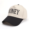 Dettaglio del ricamo HONEY su cappello da baseball bicolore beige e nero - Nero