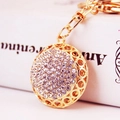 Porte-clés doré avec boule de cristal scintillante et motifs ajourés sur fond flou - Emballage Individuel / Blanc