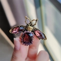 Vintage golden bee brooch with deep purple gemstones and wings in a hand-held display - Brown Bee (XZ0125)