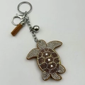 Detail of rhinestone sea turtle keychain with brown suede tassel and silver metal ring - Camel