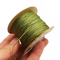 Detailed macro of grass green metallic braided cord on a kraft paper spool - Olive Green
