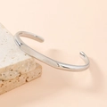 Minimalist silver stainless steel open bangle displayed on a natural stone base - Silver Smooth Style