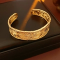 Macro shot of gold-plated cuff bracelet featuring a detailed vintage embossed texture - Gold
