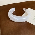 Nahaufnahme eines weißen Acryl-Armreifs mit Marmormuster auf braunem Lederhintergrund - Verstellbare Größe / Armreif-Cremeweiß