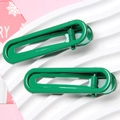 Detail of green glossy metal hair clips in U-shape design on a white textured display - Christmas Green