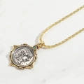 Detail eines Vintage-Münzanhängers mit grünem Edelstein an einer goldenen Kette - Quadratischer Stil