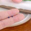 Minimalist silver stud earrings with round blue zircon stones shown on fingers - Vertical Prong No.3 / Blue