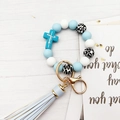 Dettaglio di perline in silicone blu con anello dorato e nappa in pelle azzurra - Blu