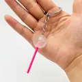 Detailed macro of a realistic transparent lollipop keychain with pink plastic stick and ring - White