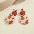 Close-up of handmade clay earrings featuring red studs and embossed orange pumpkin patterns - Orange Round Pumpkin