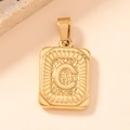 Macro shot of gold square pendant with embossed letter C and radial sunburst texture - Letter C