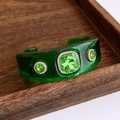 Detail einer grünen Harz-Manschette mit Smaragd-Strasssteinen auf Holztablett - Grüner Armreif Mit Grünem Stein