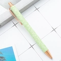 Glittery green ballpoint pen with rose gold metal accents shown on a desk - New Glitter Green