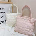 Detail of quilted floral handbag featuring plush texture and simple wish brand label - Pink