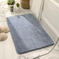 Plush gray-blue rectangular bathroom mat on marble floor in bright sunlight - Waterbird Grey Blue