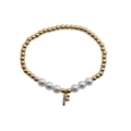 Macro detail of gold beaded bracelet with white pearls and a colorful zircon letter F charm - Letter F