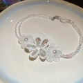 Elegante Edelstahl-Halskette mit Kristallblumen auf einem weißen Keramikteller - Halskette-Weiß