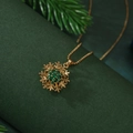 Collier flocon de neige doré rotatif avec zircons verts sur fond de branches de sapin - Flocon de Neige Vert