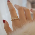 Detailaufnahme eines goldfarbenen Kreuzrings mit Zirkonia-Steinen an einer Hand - Einstellbar Offen / Gold