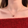 Detailansicht der vergoldeten Kette mit rotem Pony und Herz auf rotem Pullover - Gold