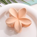 Détail d'une pince à cheveux fleur de frangipanier rose mat sur une assiette blanche - Rose poudré