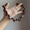 Détail d'un collier vintage avec cubes en acrylique léopard et perles en bois brun - Style Léopard Or-Marron