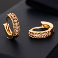 Elegante goldene Huggie-Ohrringe mit Zirkon-Mikropavé und Perlenrand auf dunklem Hintergrund - Doppelreihiger Zirkonia / Gold