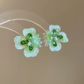Vista macro degli orecchini a fiore in argento con petali verdi cangianti e cristalli - Verde