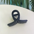 Gros plan d'une pince à cheveux torsadée noire mate avec design antidérapant élégant - Moyen / Noir mat