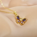 Primer plano de un collar de mariposa dorado con piedras púrpuras sobre seda suave - Morado