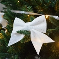 Sparkling white sequined Christmas bow ornament hanging on a festive green pine tree branch - White Small Bowknot Set of 4 15CM