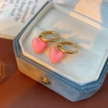 Detail van roze emaille hart oorbellen met gouden ringen in een fluwelen doosje - Gouden Huggie-Roze