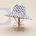 White bucket hat with black heart pattern and adjustable chin strap on a stand - Heart Style / White