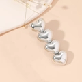 Eleganter Vier-Herz-Haarclip aus Silberlegierung mit polierter Oberfläche auf Beige - Silber