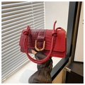 Close-up of red crocodile texture bag with woven handle and gold metal hardware - Red