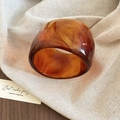 Detail of amber acrylic resin cuff bracelet with tortoiseshell pattern on linen fabric - Coffee - Wide Surface