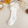 Close-up of baby knee high socks with large velvet bows on warm knit background - White / Xs 0-1