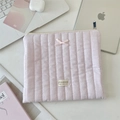 Détail d'une housse d'ordinateur rose matelassée avec nœud et accessoires sur un bureau - Rayures Roses