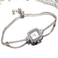 Detail of square silver watch with rhinestone bezel and adjustable bracelet strap on mirror - Silver
