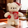 Weißer Teddybär mit Weihnachtsmütze und kariertem Schal hält eine rote Weihnachtskugel - Stil Mit Rotem Schal Und Großen Schneeflocken