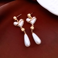 Detailed view of vintage pearl heart drop earrings with gold finish on dark fabric - Gold