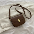 Retro caramel brown saddle crossbody bag with a gold buckle on a beige suit background - Dark Brown