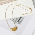 Close-up of golden heart pendant necklace with a white pearl on elegant silk background - Heart Necklace / Gold