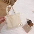 Gros plan sur le sac à main en velours côtelé crème avec rayures et étiquette tissée - Blanc laiteux