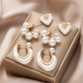 Dettaglio di tre set di orecchini dorati con perle su un elegante portagioie in oro - Set di Gioielli in Perle Artificiali Cuore (5933401HB) / Oro