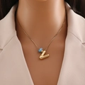 Close-up of golden letter Z pendant and blue evil eye bead on a sleek necklace - Gold Letter V