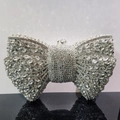 Detailed close-up of a silver bow clutch bag covered in shimmering rhinestones and crystals - Silver