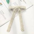 Macro detail of elegant bow hair clip with faux pearls and rhinestones on a magazine - White Pearl Beaded Bow Clip