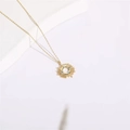 Collier pendentif soleil en plaqué or 14K avec zircons turquoise sur un fond blanc - Soleil Creux